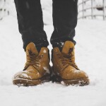 An image showing boots of a man who is stood in snow