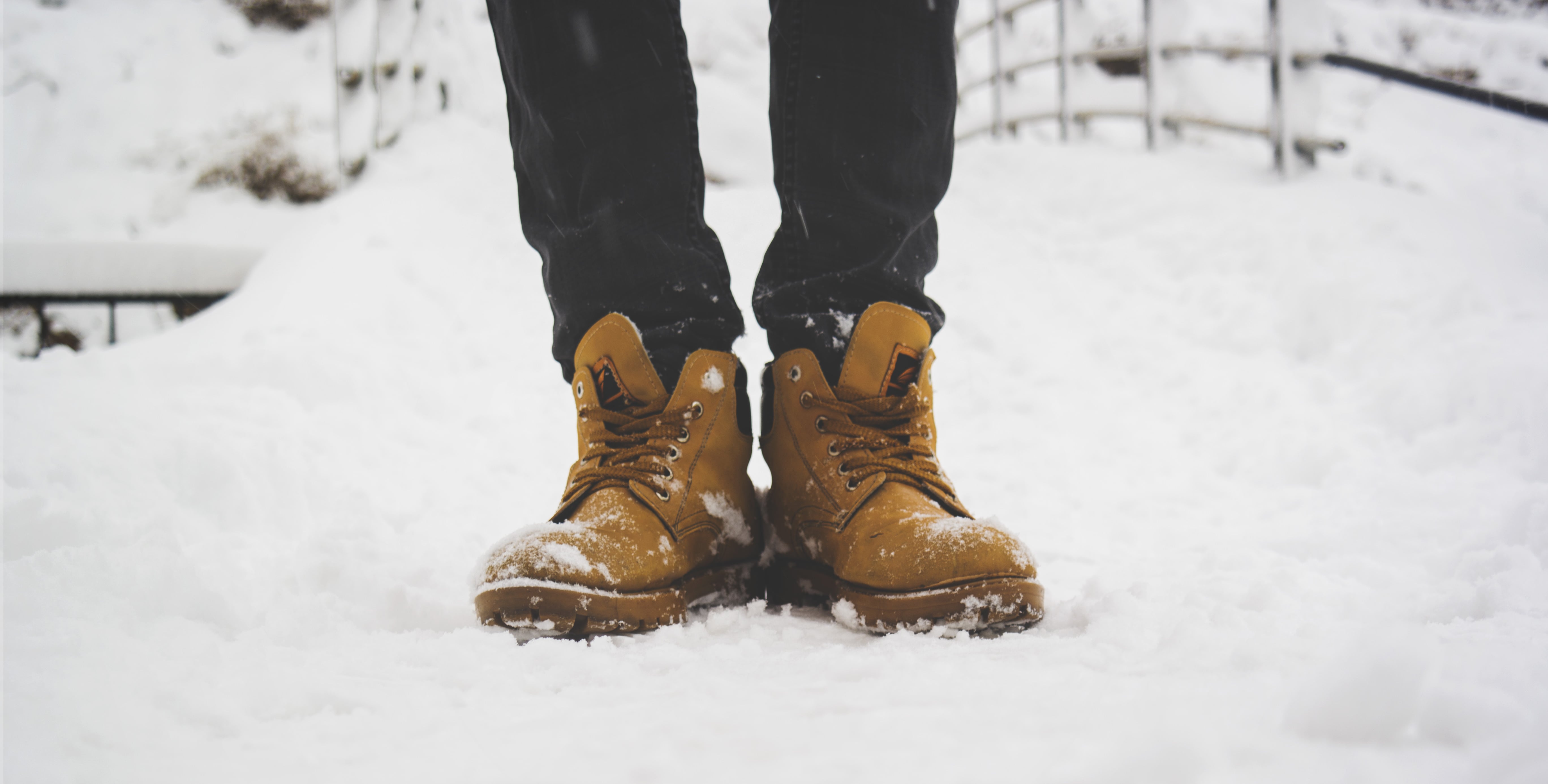 An image showing boots of a man who is stood in snow